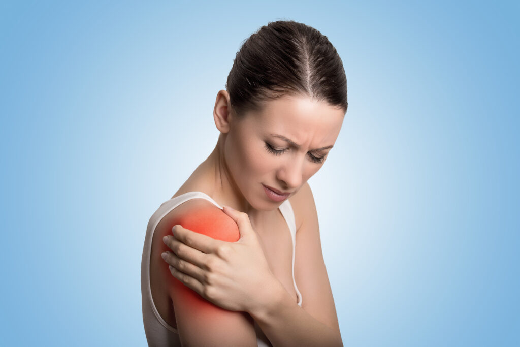 Injured joint. Young woman patient in pain having painful shoulder colored in red. Medicine and health care concept. Blue background