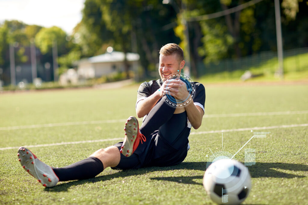 sport, sports injury and people - injured soccer player with ball on football field