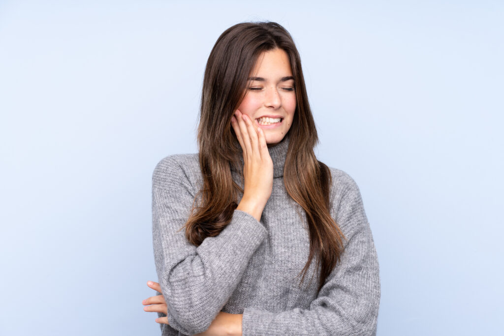 girl holding jaw due to joint pain and TMJ